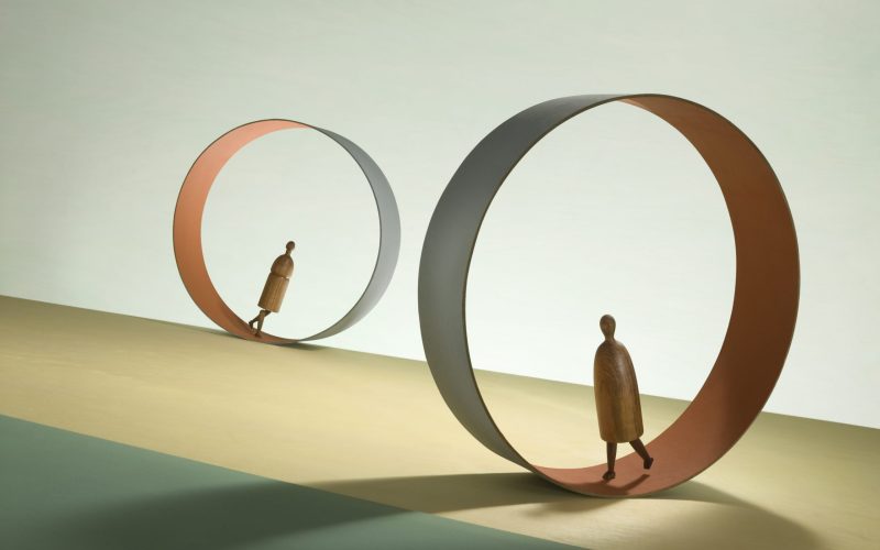 Two figures march inside endless treadmills.