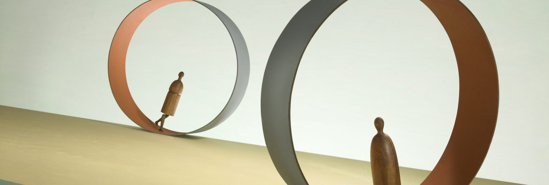 Two figures march inside endless treadmills.