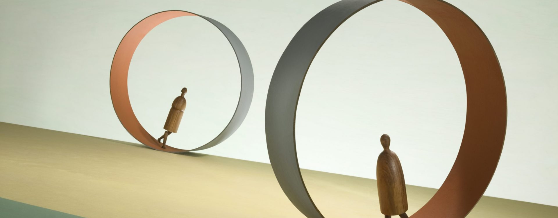 Two figures march inside endless treadmills.